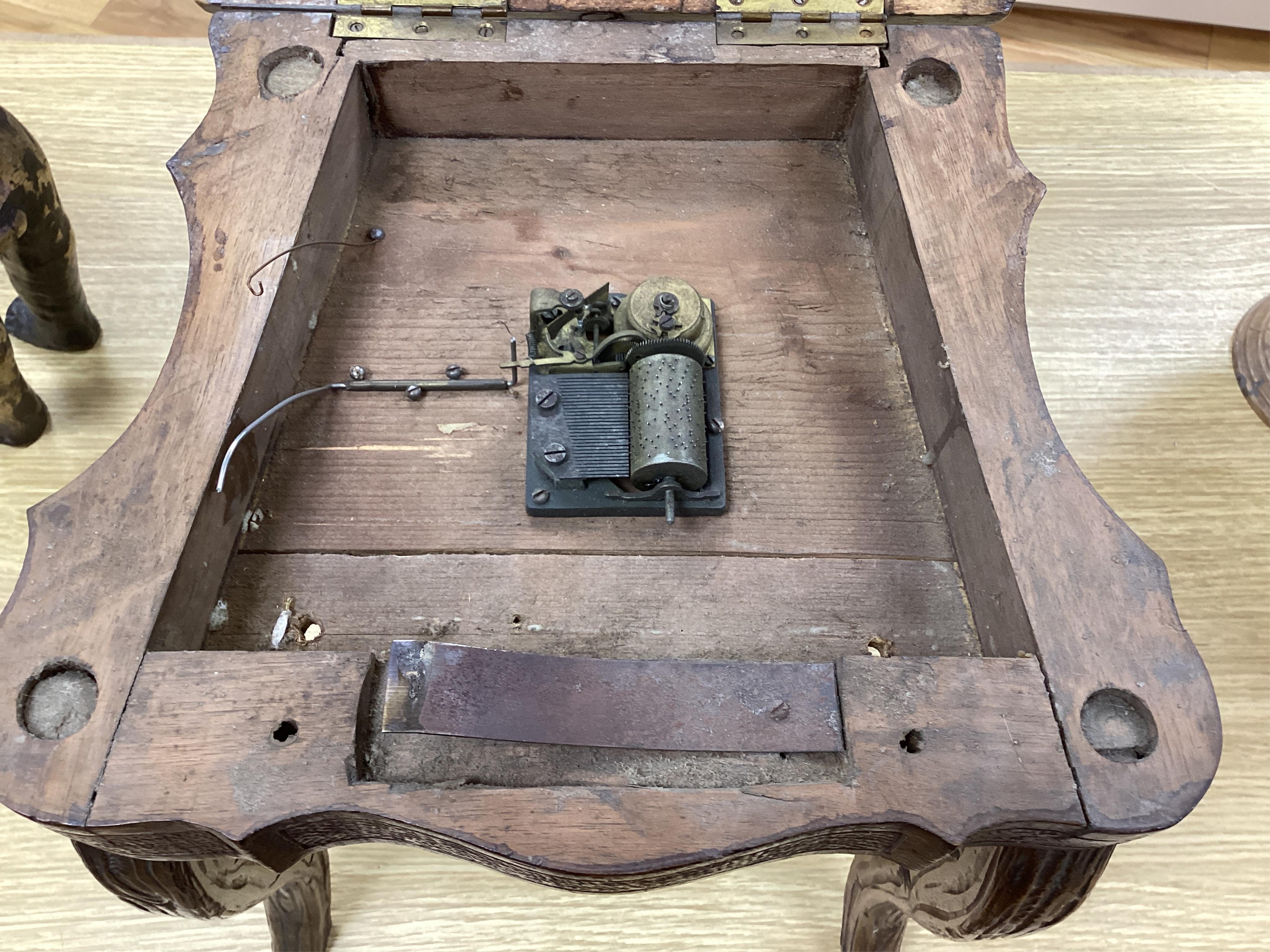 A 19th century Black Forest carved child’s musical chair with integral music box, the seat and back each inlaid with an animal cartouche, 68cm high